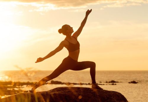 Kvinna yogar i solnedgången