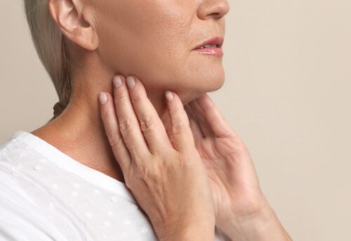 kvinna tar sig på halsen på sköldkörteln